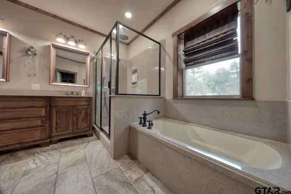 a spacious bathroom with a tub sink and mirror