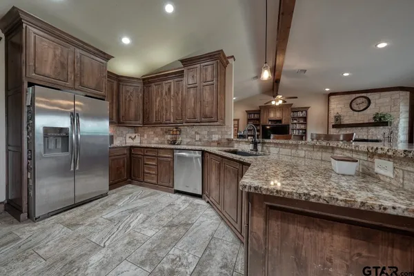 a kitchen with stainless steel appliances granite countertop a sink refrigerator and cabinets