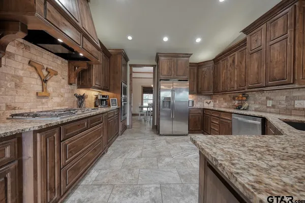 a kitchen with stainless steel appliances granite countertop a sink a stove and a refrigerator