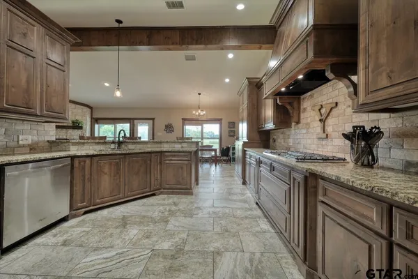 a kitchen with stainless steel appliances granite countertop a stove a sink dishwasher and a refrigerator