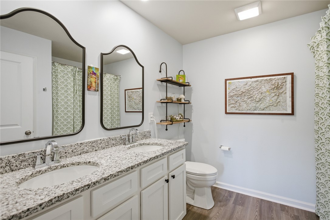 412 Chadwick Lane Walhalla, SC 29691 - Photo 16 of 37 This bathroom features a double vanity with granite counters and rich hardwood-style flooring, creating a modern and functional space.