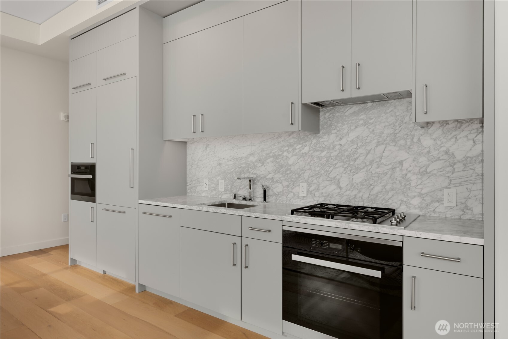 121 Stewart Street, Unit 3504 Seattle, WA 98101 - Photo 11 of 31 a kitchen with white cabinets and a stove with wooden floor
