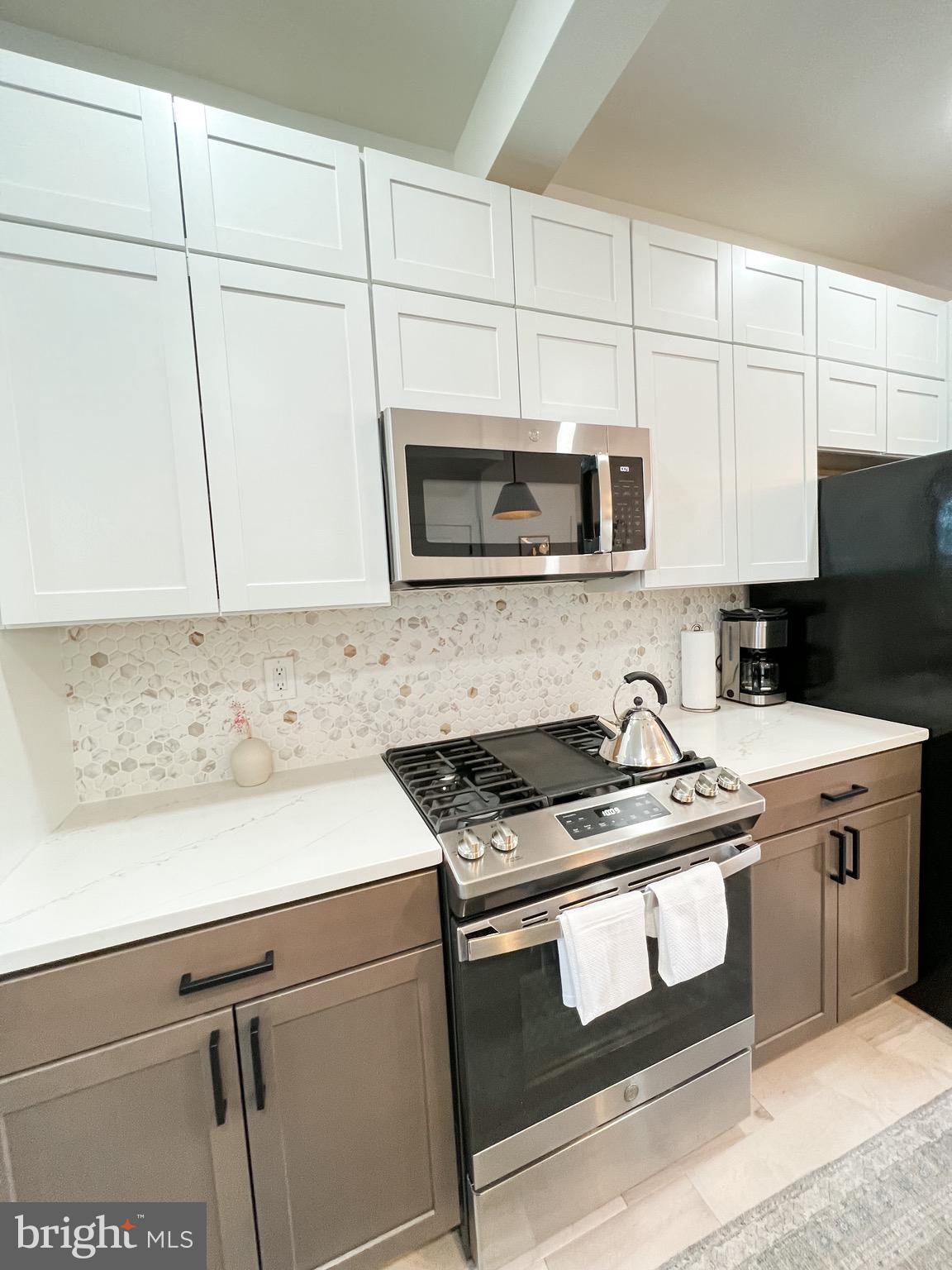 3424 9th Street Northeast Washington, DC 20017 - Photo 8 of 32 a kitchen with granite countertop a stove top oven microwave and cabinets