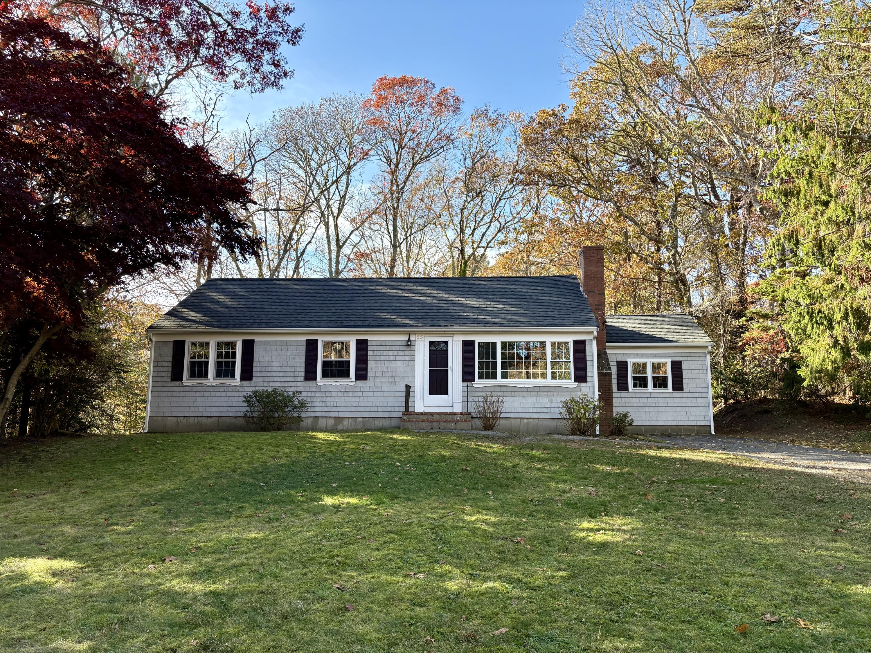 a house that is sitting in the grass with large trees