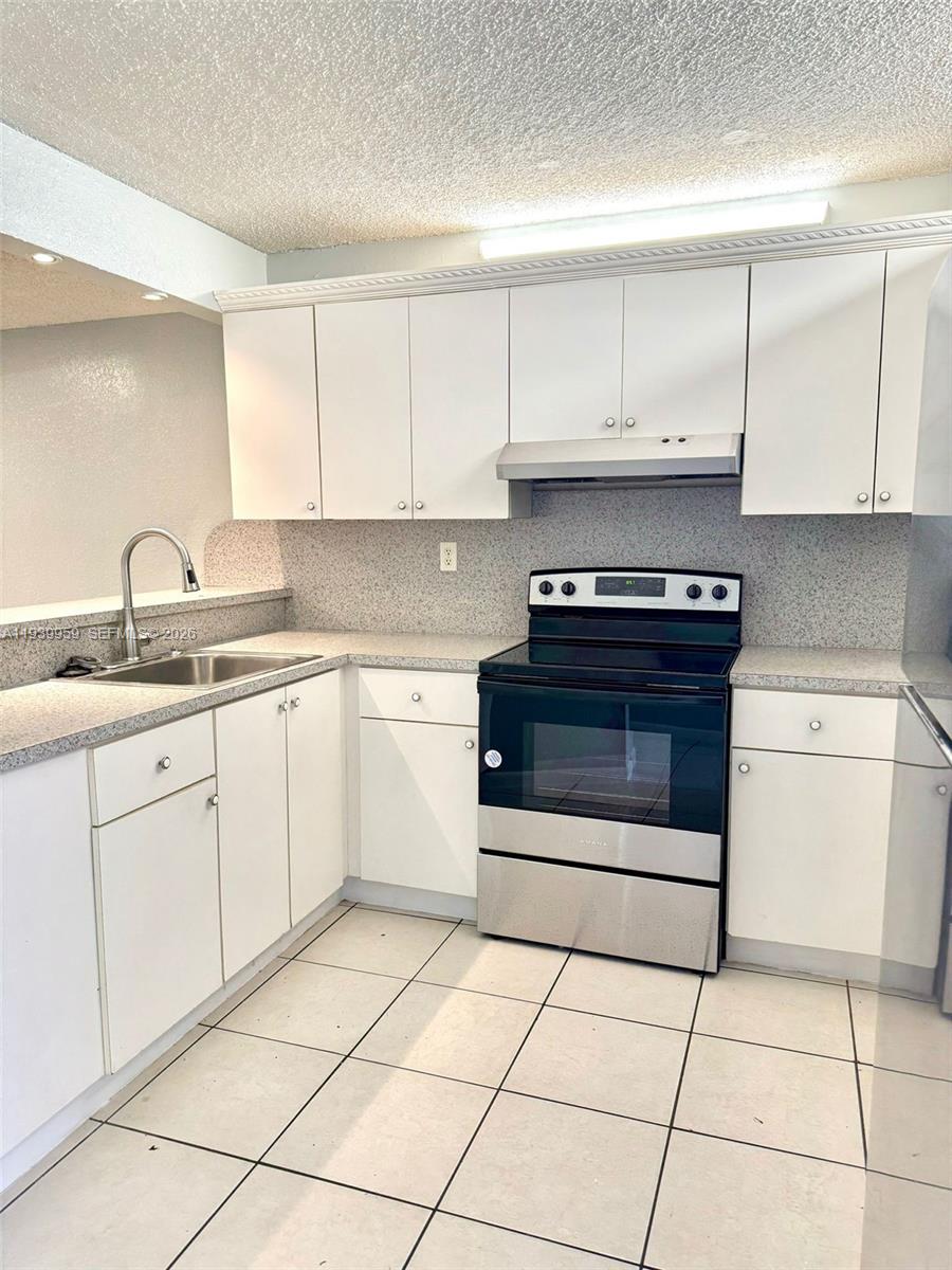 220 West 68th Street, Unit 101 Hialeah, FL 33014 - Photo 3 of 28 a kitchen with a stove sink and cabinets