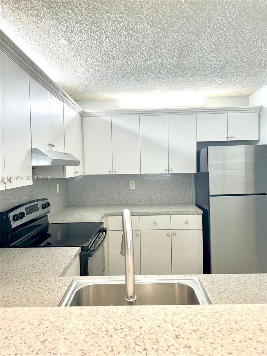 220 West 68th Street, Unit 101 Hialeah, FL 33014 - Photo 4 of 28 a kitchen with a refrigerator and cabinets