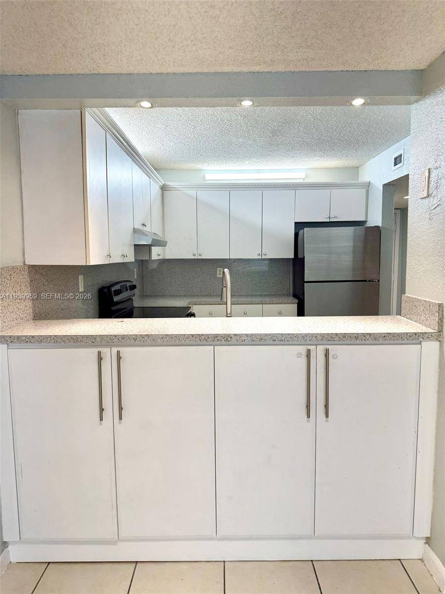 220 West 68th Street, Unit 101 Hialeah, FL 33014 - Photo 5 of 28 a kitchen with granite countertop white cabinets and refrigerator