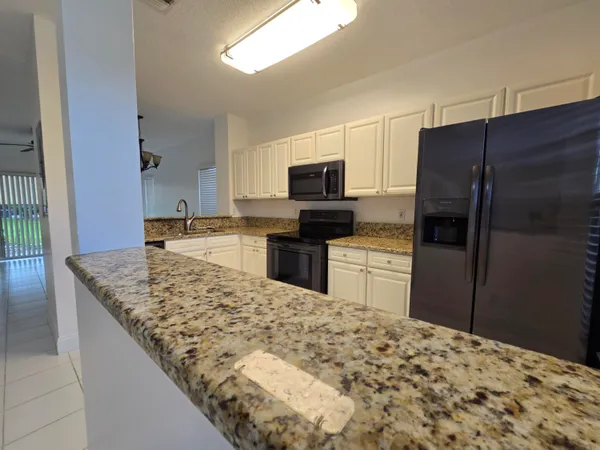 a kitchen with stainless steel appliances kitchen island granite countertop a refrigerator and a sink