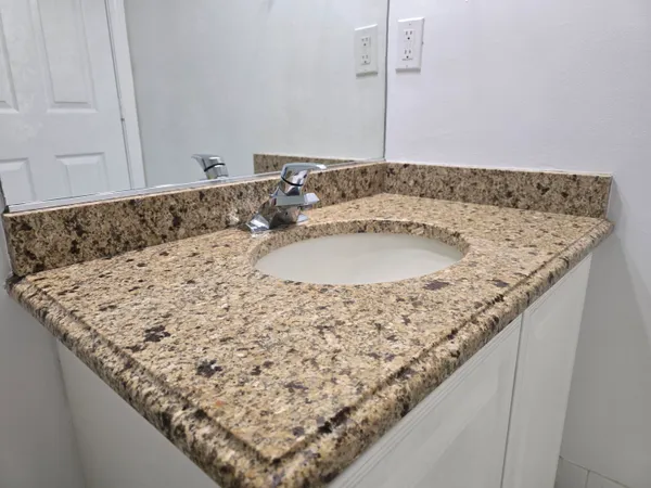 a bathroom with a granite countertop sink and mirror