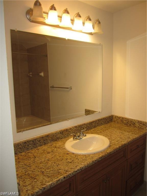 8560 Violeta Street, Unit 104 Estero, FL 34135 - Photo 6 of 12 a bathroom with a granite countertop sink and a mirror