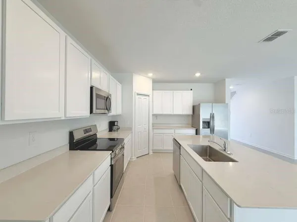 a kitchen with stainless steel appliances granite countertop a sink dishwasher a refrigerator a microwave oven with white cabinets and granite countertops