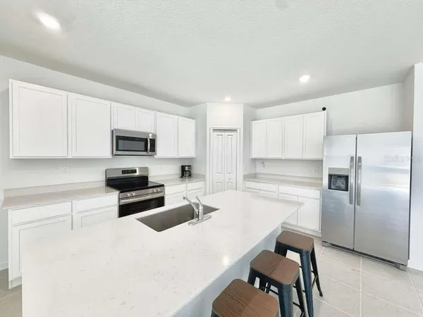 a kitchen with stainless steel appliances a refrigerator a stove a sink a dining table and chairs