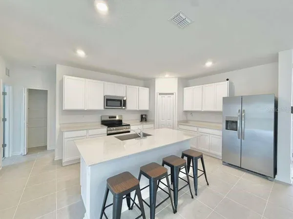 a kitchen with stainless steel appliances a refrigerator sink and white cabinets