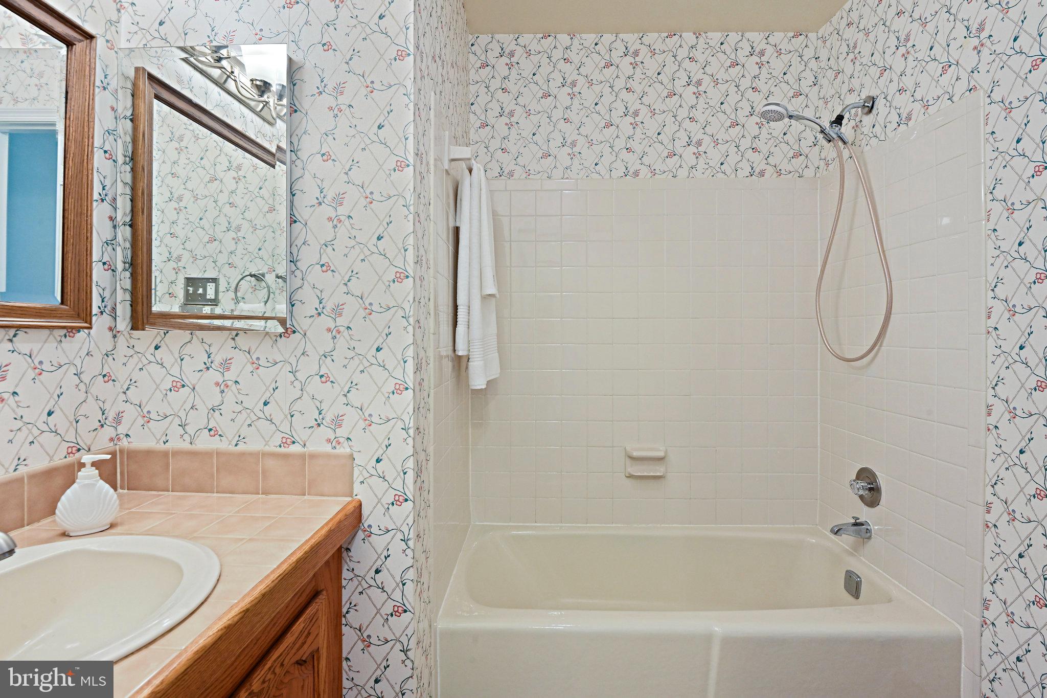 2180 Golf Course Drive Reston, VA 20191 - Photo 24 of 40 a bathroom with a granite countertop sink a mirror and a bathtub