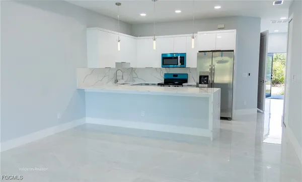 a view of kitchen with stainless steel appliances granite countertop a refrigerator a sink and a stove