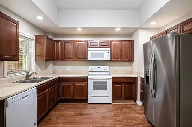 a kitchen with stainless steel appliances granite countertop wooden cabinets a sink and dishwasher a stove with wooden floor