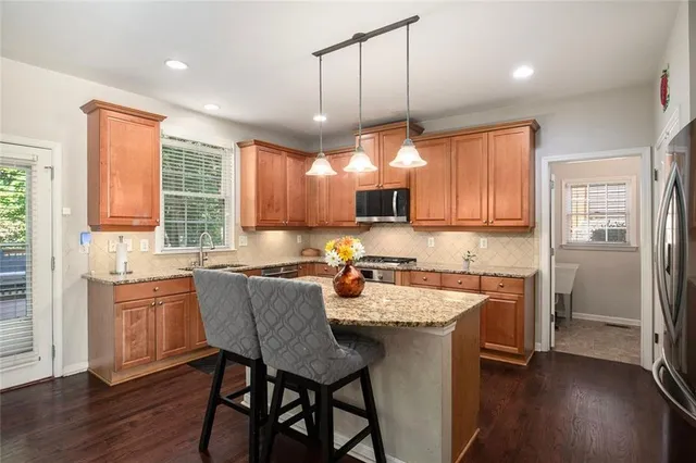 a kitchen with a refrigerator a sink dishwasher a dining table and chairs with wooden floor