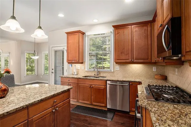 a kitchen with stainless steel appliances kitchen island granite countertop a sink a stove a oven a counter space and cabinets