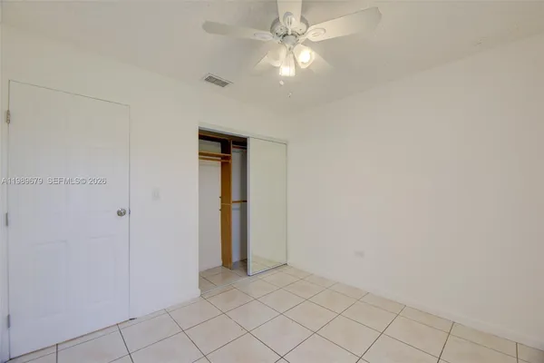 an empty room with closet and a ceiling fan