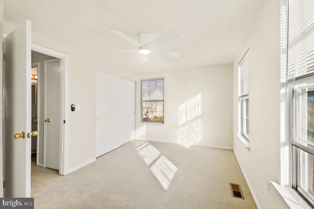 a view of empty room with wooden floor and fan