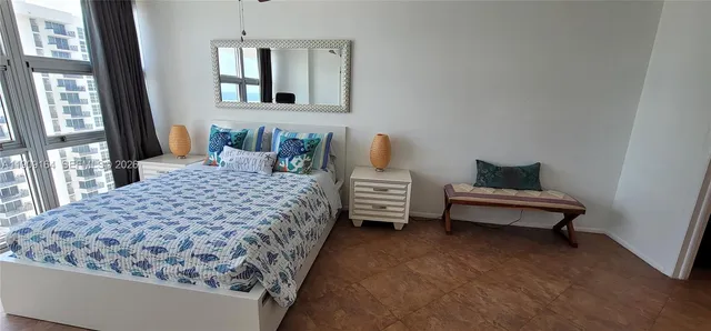 a bedroom with a bed and large windows