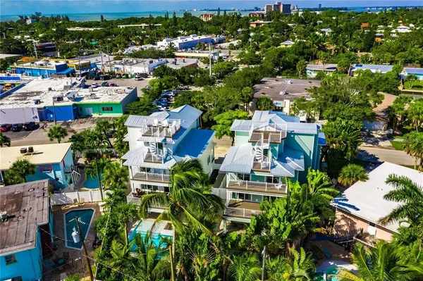 an aerial view of residential houses with outdoor space and trees