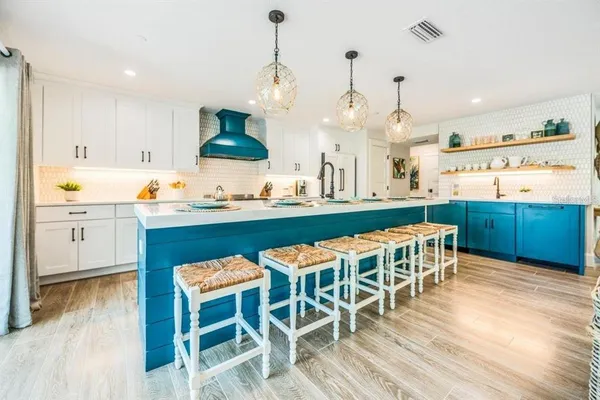 a dining table with wooden floor and kitchen view