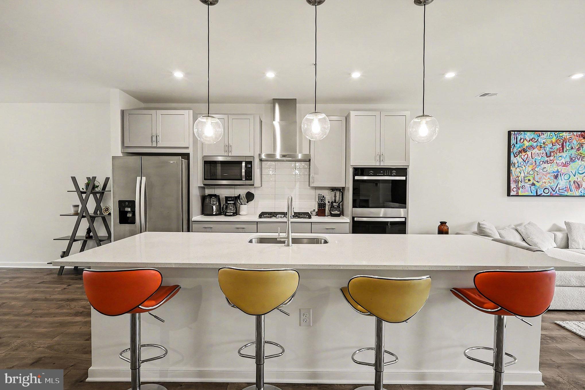 45956 Swallow Terrace Sterling, VA 20165 - Photo 3 of 29 a kitchen with stainless steel appliances kitchen island granite countertop a kitchen island a table and chairs