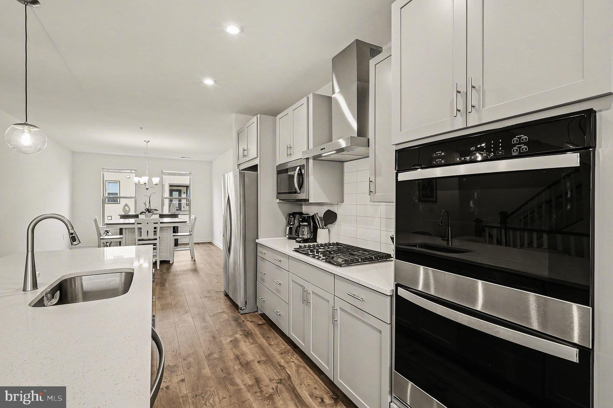 45956 Swallow Terrace Sterling, VA 20165 - Photo 5 of 29 a kitchen with stainless steel appliances kitchen island granite countertop a stove a sink and a microwave