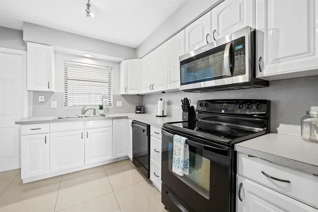 a kitchen with stainless steel appliances granite countertop grey cabinets a stove a sink and dishwasher