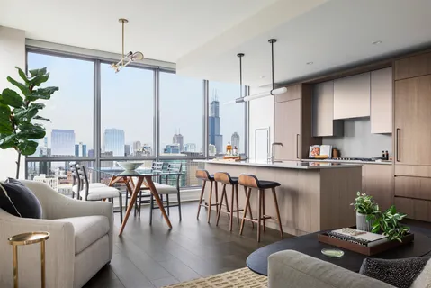 a kitchen with stainless steel appliances granite countertop a stove a refrigerator a couch a dining table and chairs with wooden floor