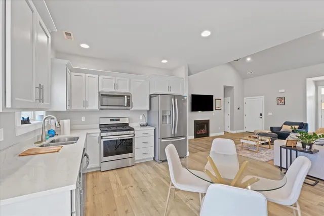 a kitchen with stainless steel appliances granite countertop a stove top oven a sink dishwasher a dining table and chairs with wooden floor