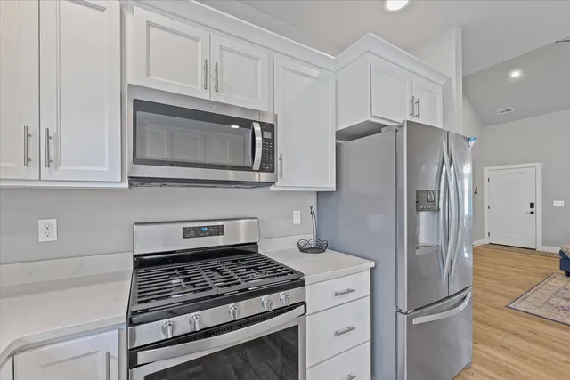 a kitchen with stainless steel appliances granite countertop a refrigerator stove and cabinets