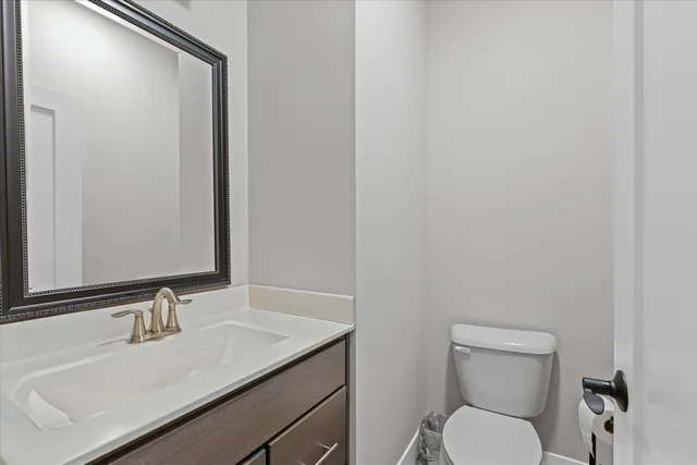 a bathroom with a granite countertop sink toilet and mirror