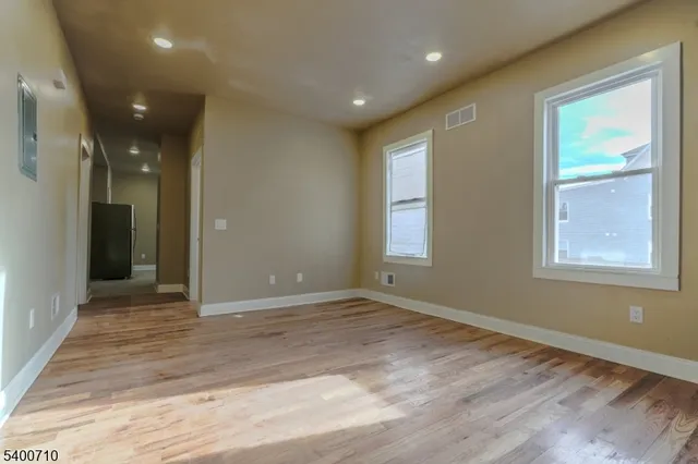 a view of empty room with wooden floor and fan