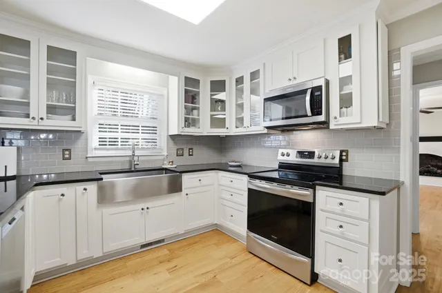 a kitchen with granite countertop white cabinets a sink a window and stainless steel appliances