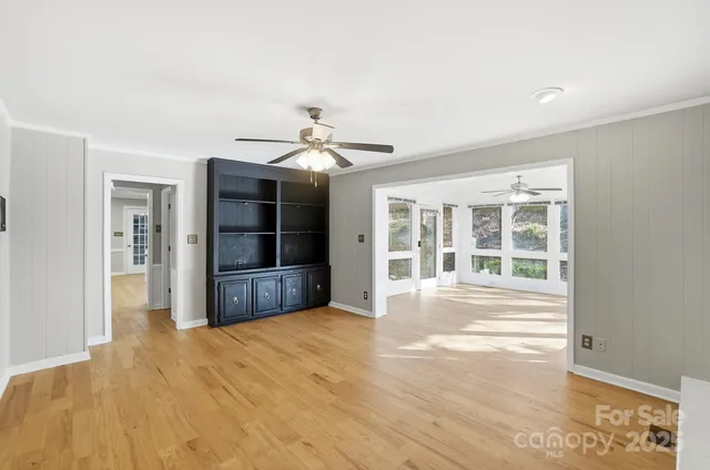 a view of an empty room with a window and kitchen view
