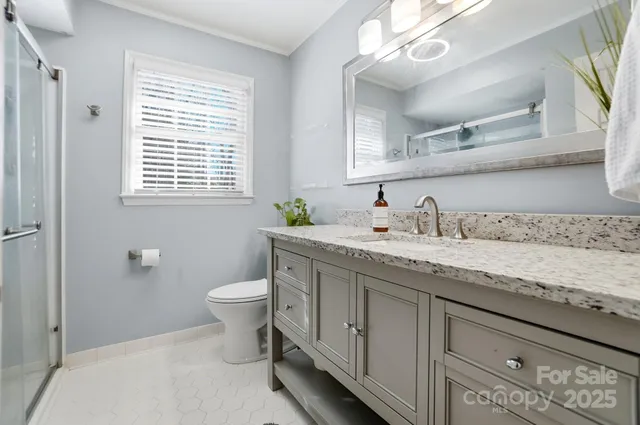 a bathroom with a granite countertop sink a toilet and a window