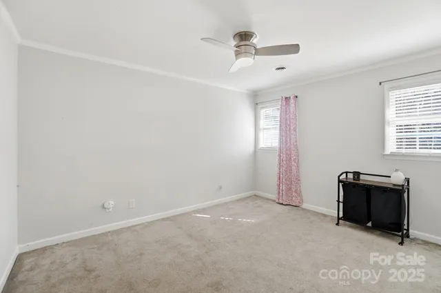 an empty room with a ceiling fan and windows