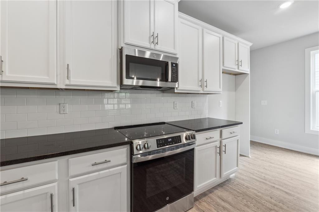 2546 Harbor Ridge Pass, Unit 341 Gainesville, GA 30507 - Photo 7 of 41 a kitchen with stainless steel appliances granite countertop a stove a microwave and a white cabinets