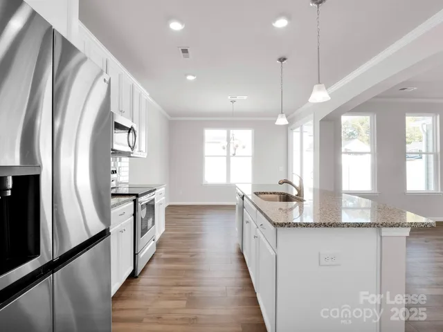 a view of a kitchen with granite countertop a sink and a refrigerator