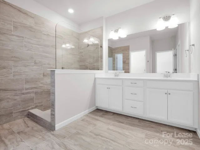 a bathroom with a double vanity sink a mirror and a shower