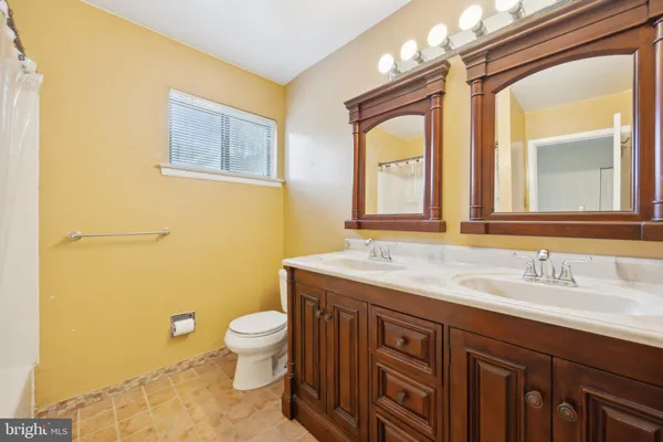 a bathroom with a granite countertop toilet a sink a mirror and a window