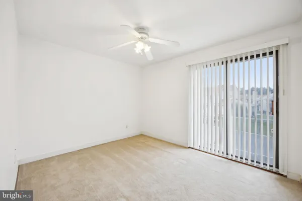 an empty room with a chandelier fan and windows