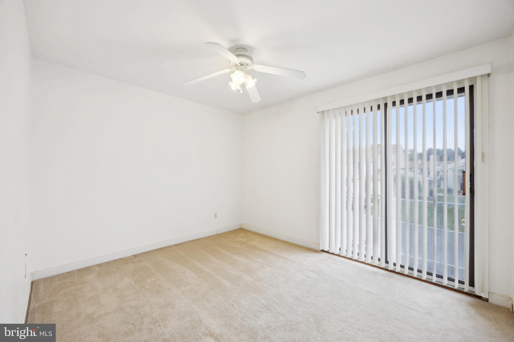 105 Grant Road Lansdale, PA 19446 - Photo 10 of 15 an empty room with a chandelier fan and windows