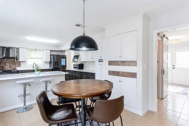 a kitchen with stainless steel appliances a dining table chairs and white cabinets