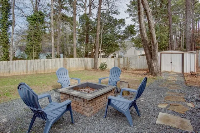 a view of a backyard with table and chairs under an umbrella with large trees