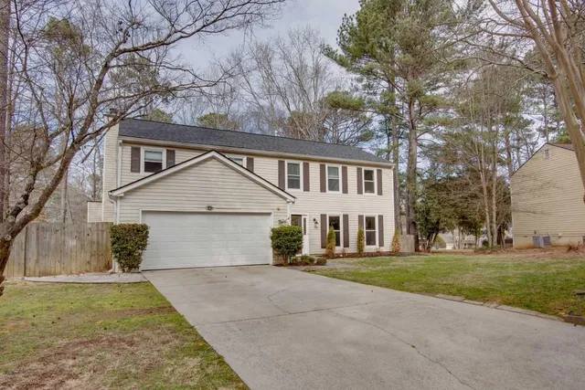 a view of a house with a yard and large tree