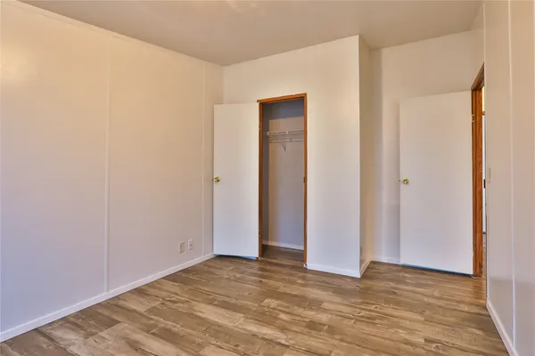a view of an empty room with wooden floor and closet