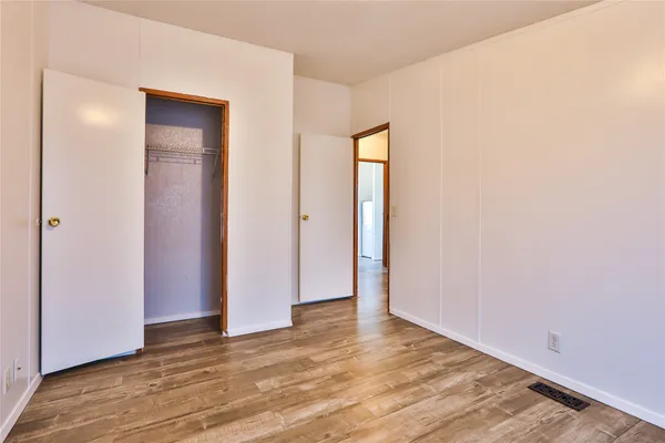 a view of an empty room with wooden floor and closet